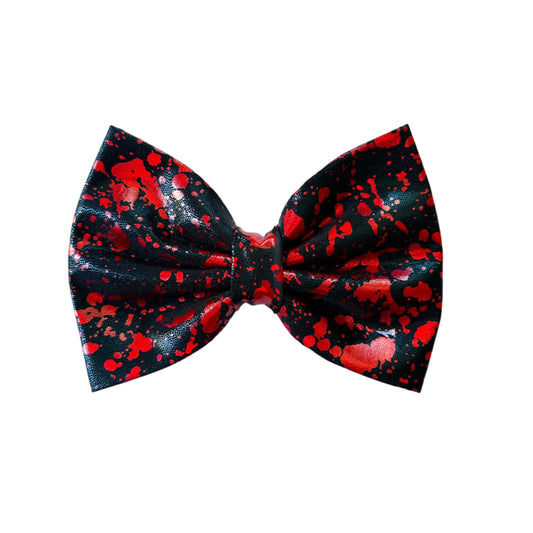 Black bow tie with red splatter pattern on a white background